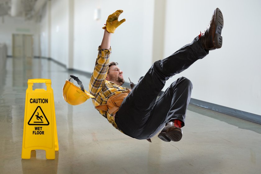 Worker slipping beside a wet floor caution sign